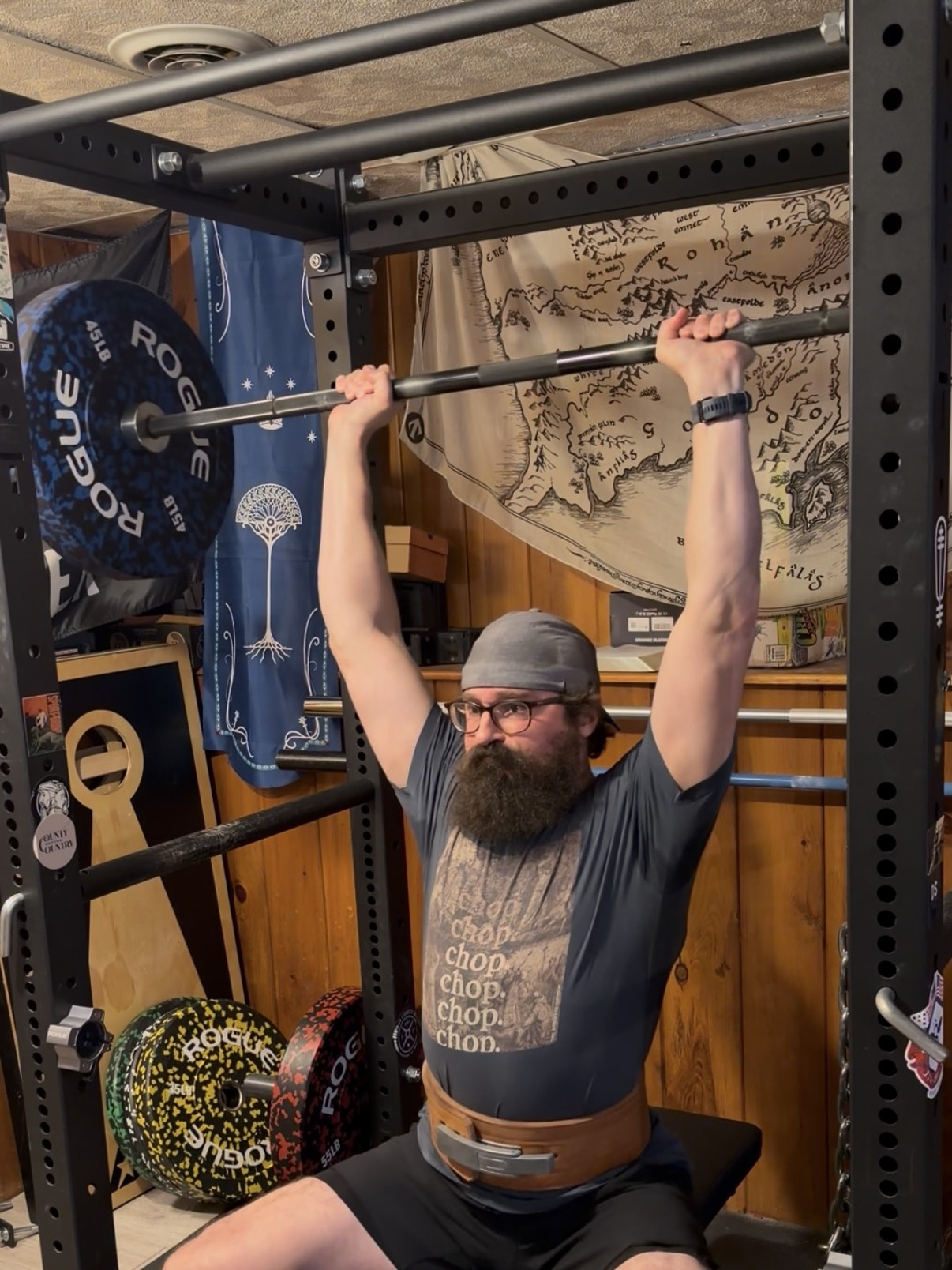 Matthew Majeika pressing a loaded barbell overhead in his home gym